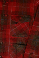 Close-up of a red plaid shirt with buttons and a pocket.