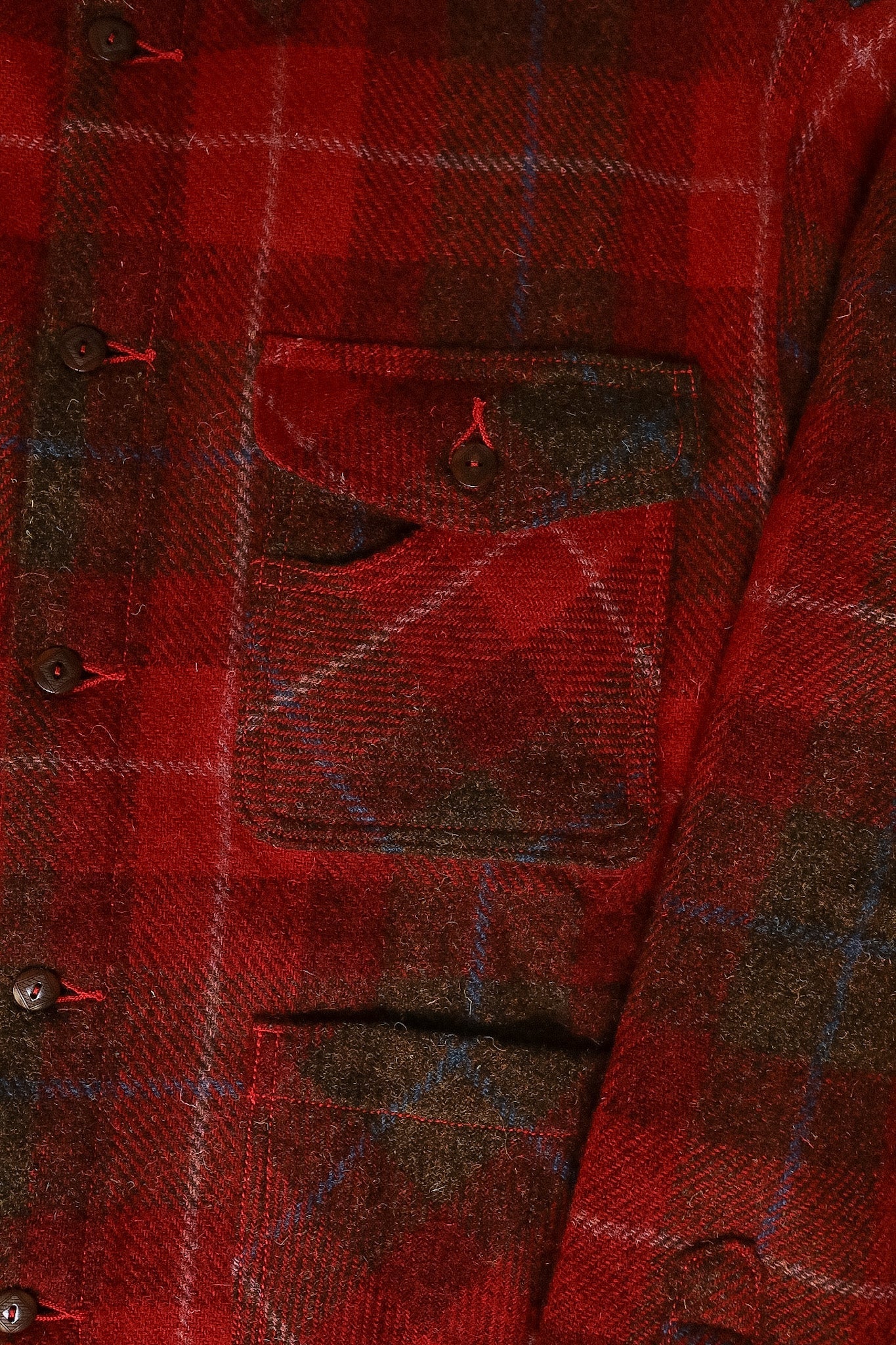 Close-up of a red plaid shirt with buttons and a pocket.