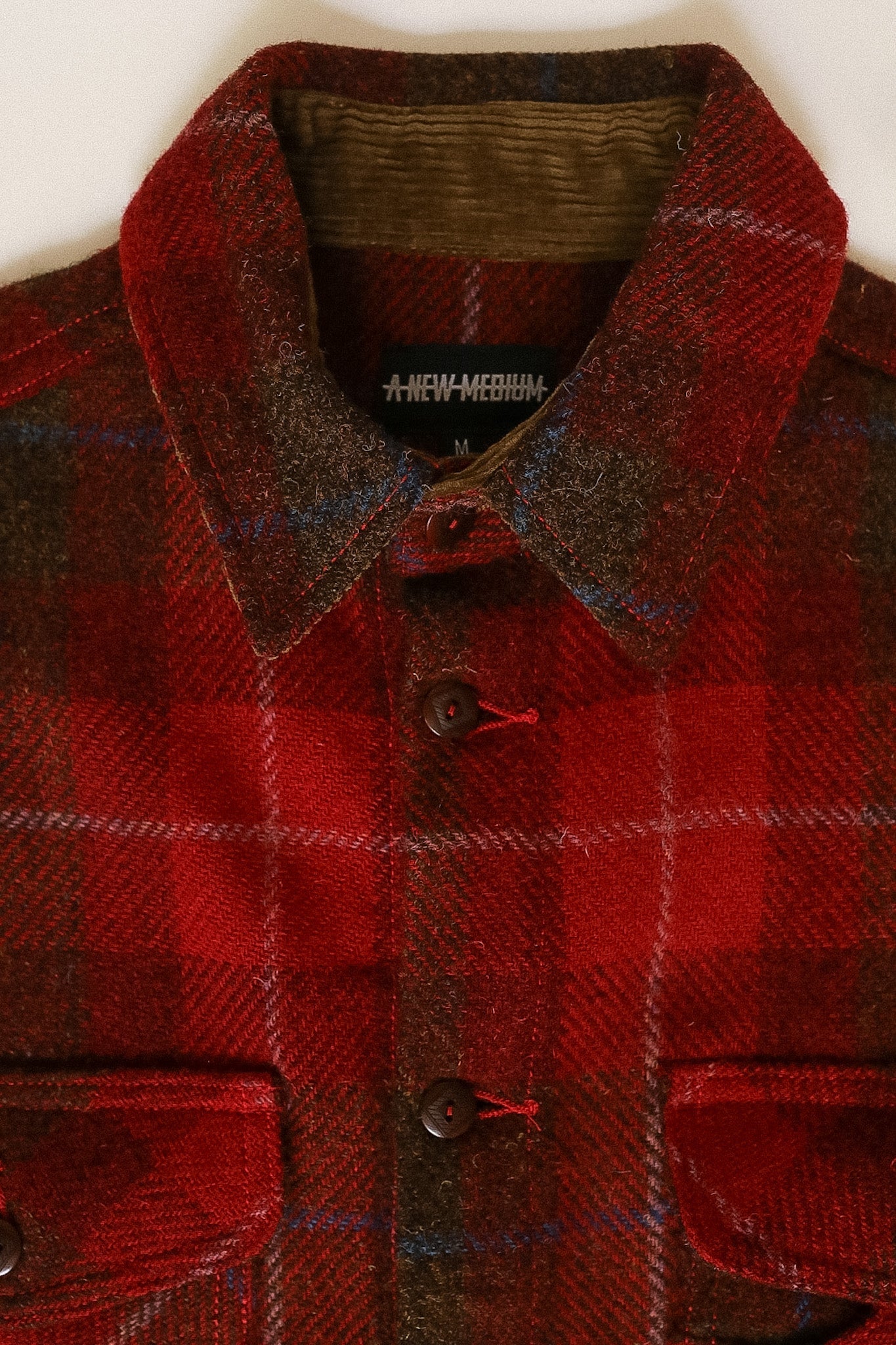Red plaid jacket with a collar and buttons, brand visible on collar.