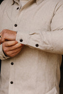 Close-up of man adjusting cuff on cream flannel Oxford shirt with dark buttons at Iron Shop Provisions