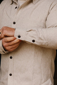 Close-up of man adjusting cuff on cream flannel Oxford shirt with dark buttons at Iron Shop Provisions