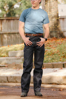 Man wearing wide straight 16.5oz indigo Kaisen denim jeans with brown belt and teal t-shirt outdoors