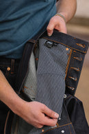 Close-up of hands holding Indigo 16.5oz Kaisen denim jeans showing striped inner lining and button fly