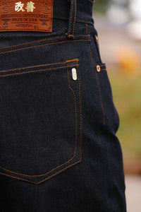 Close-up of Iron Shop Provisions dark indigo denim jeans with orange stitching and leather patch on back pocket